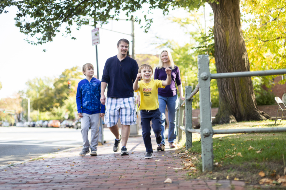 Two parents and two boys walk down a brick street in Harvard Square