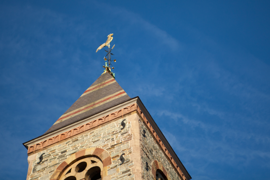 The tower of First Church Cambridge showing its rooster weathervane against a blue sky