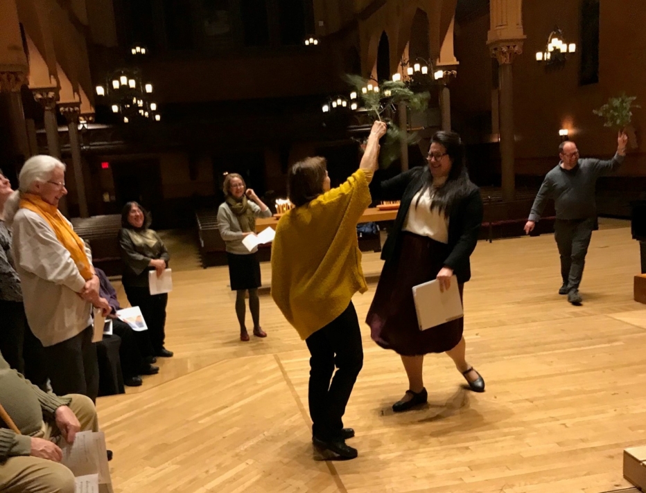 two women sprinkle water from pine branches in Epiphany service