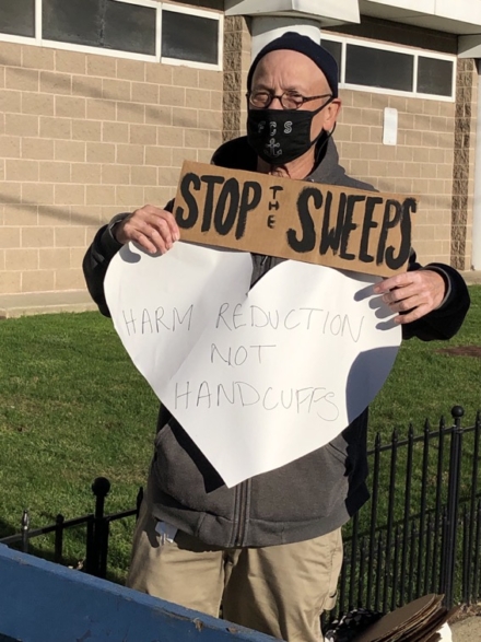 director holding sign that says Stop the Sweeps